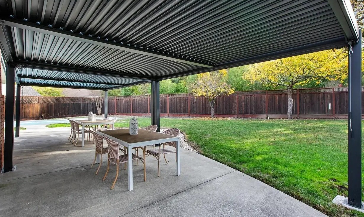 Covered patio with adjustable louvered roof looking over the lawn and pool