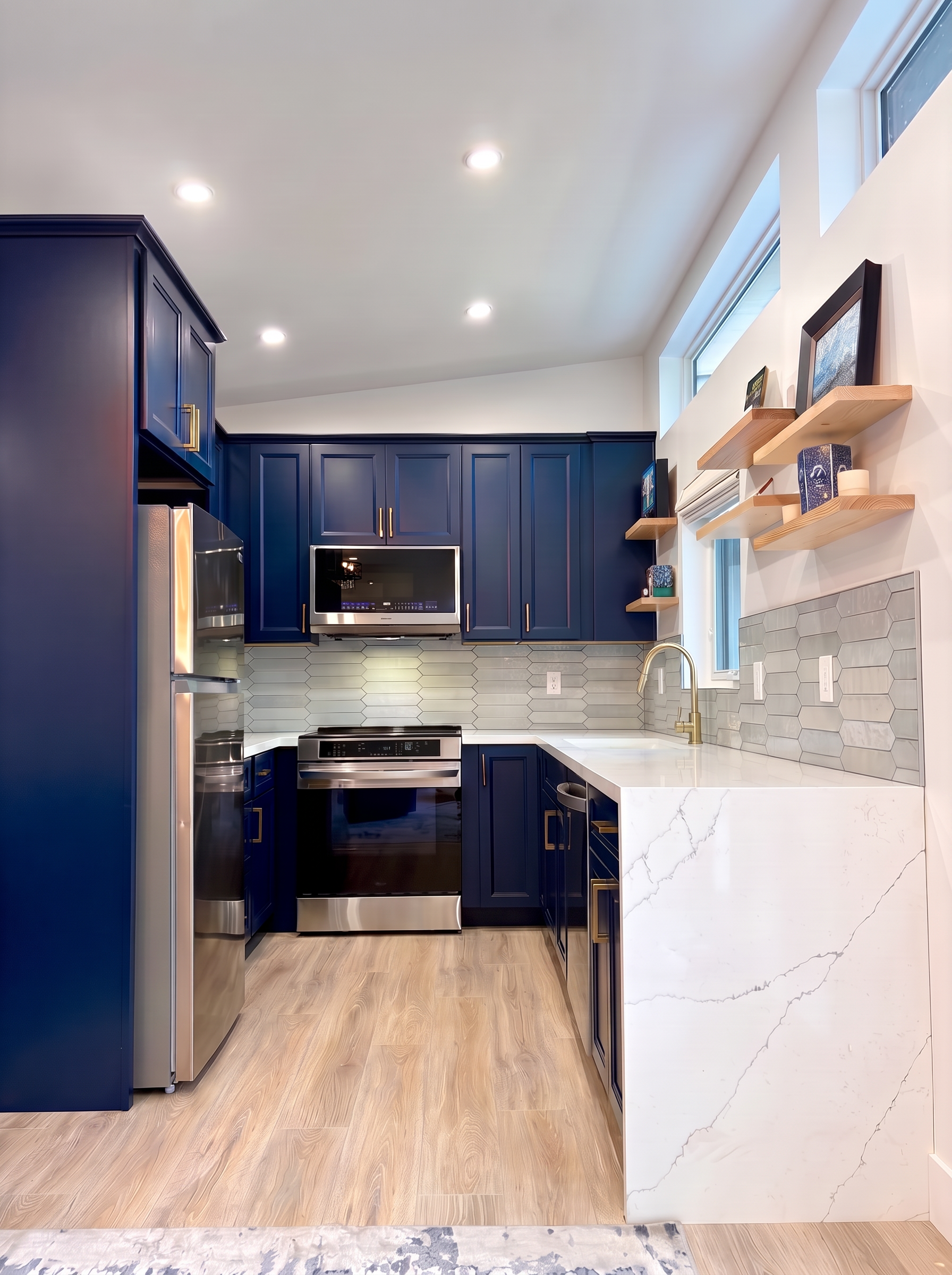 ADU kitchen with navy cabinetry, brass hardware, and waterfall quartz countertop