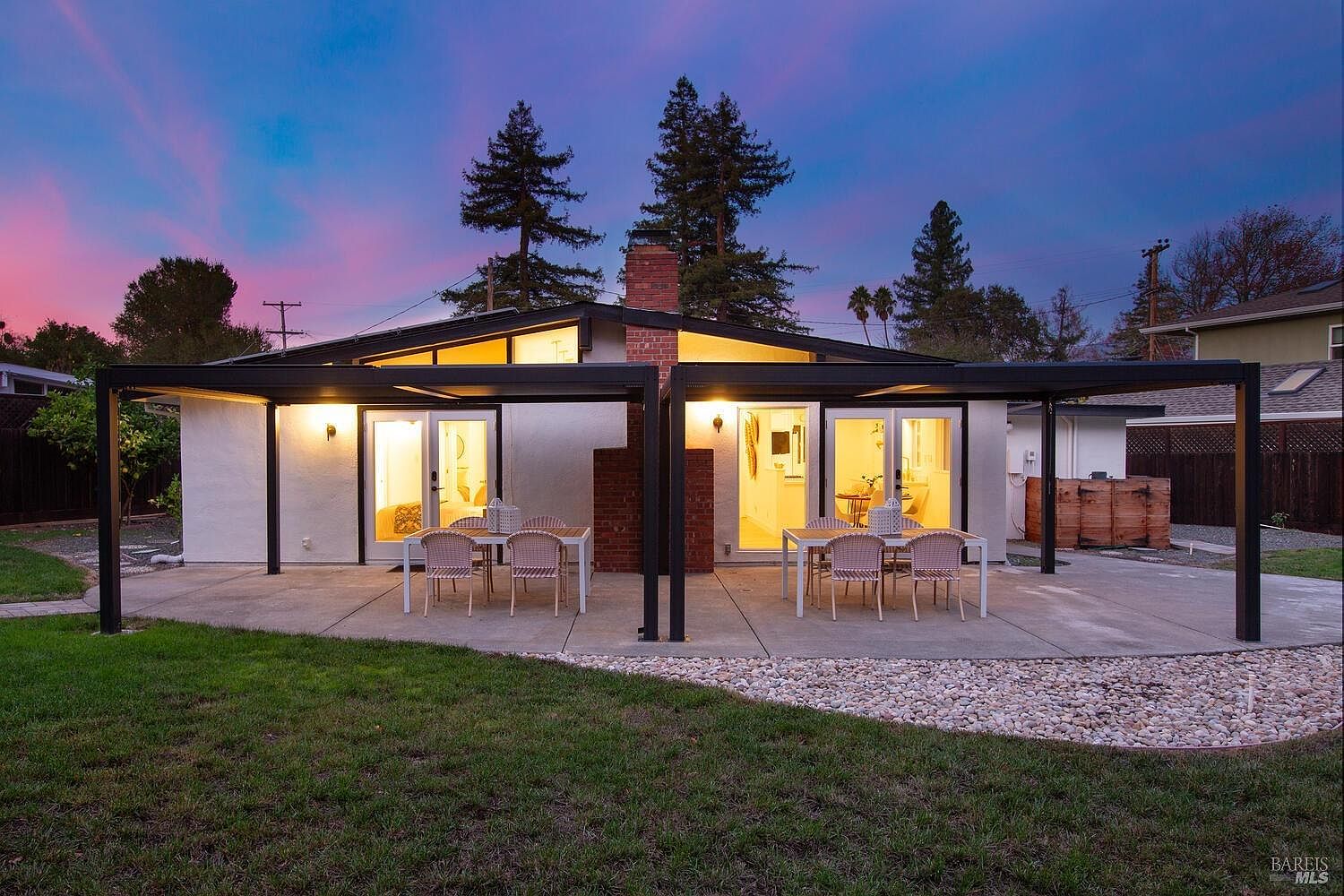 Covered patio with adjustable louvered roof at twilight